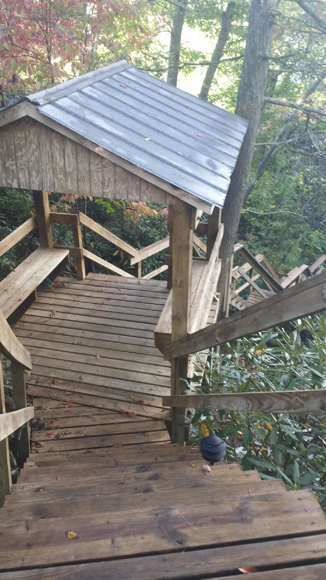 Metal roofed shelter over wooden steps on a wooded walkway — Skylight Repair & Installation work by our crew in Colton